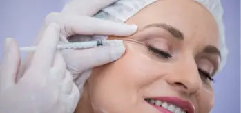 Receiving an injection near her eye to treat crow's feet.