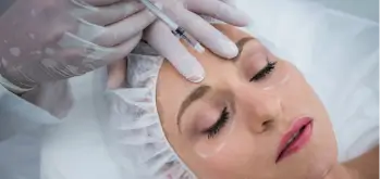 Woman smiling as she receives a Dysport injection near her eye