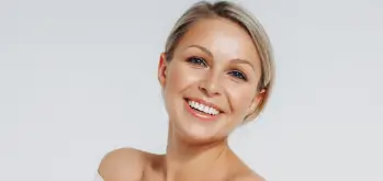 Woman showcasing results of Ozempic face treatment on a light grey